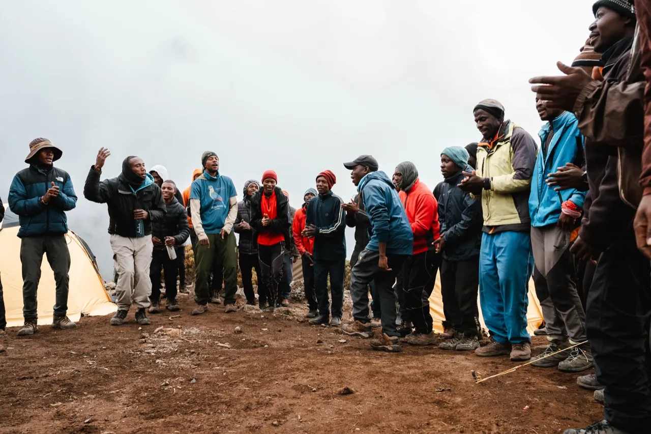 Kilimanjaro porters and camp crew singing and dancing together for trekkers at a high-altitude camp